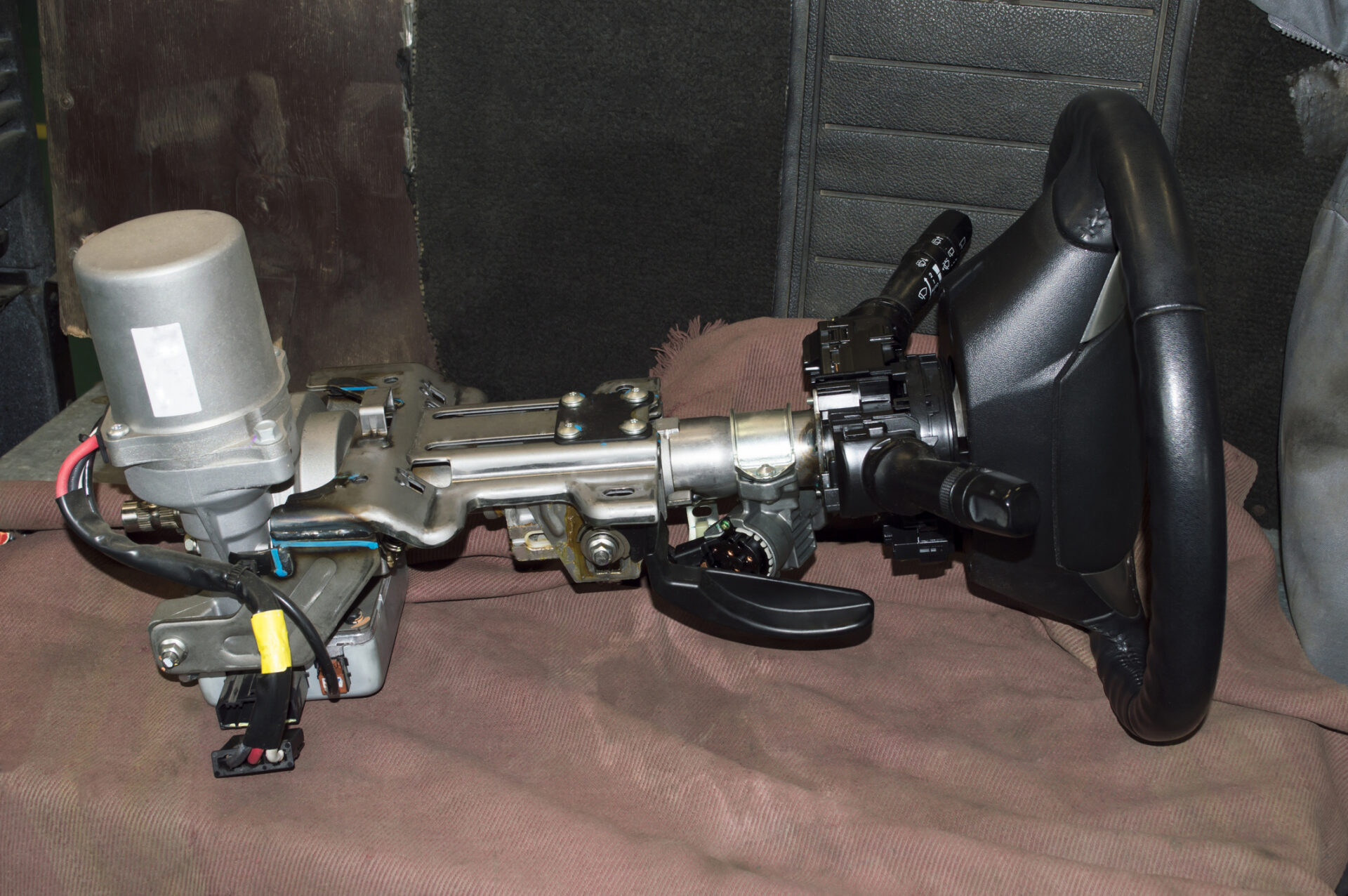 This image shows a car steering column assembly with a steering wheel, turn signal, and wiper control stalks, possibly removed for repair or replacement.